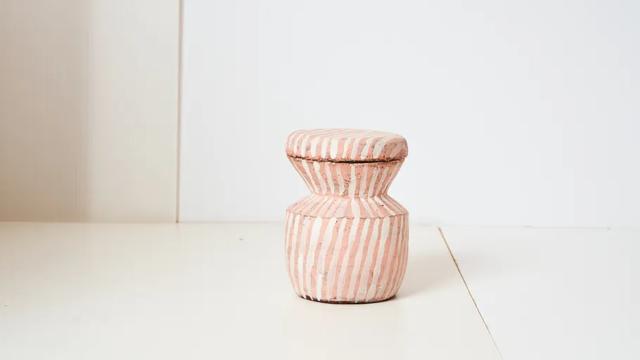 Striped ceramic jar on white surface.