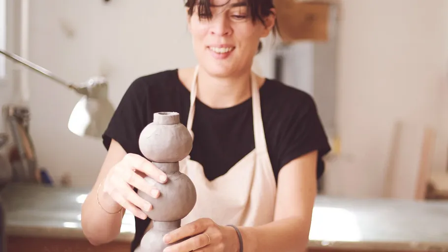 Frau formt Ton in einem Töpferstudio.
