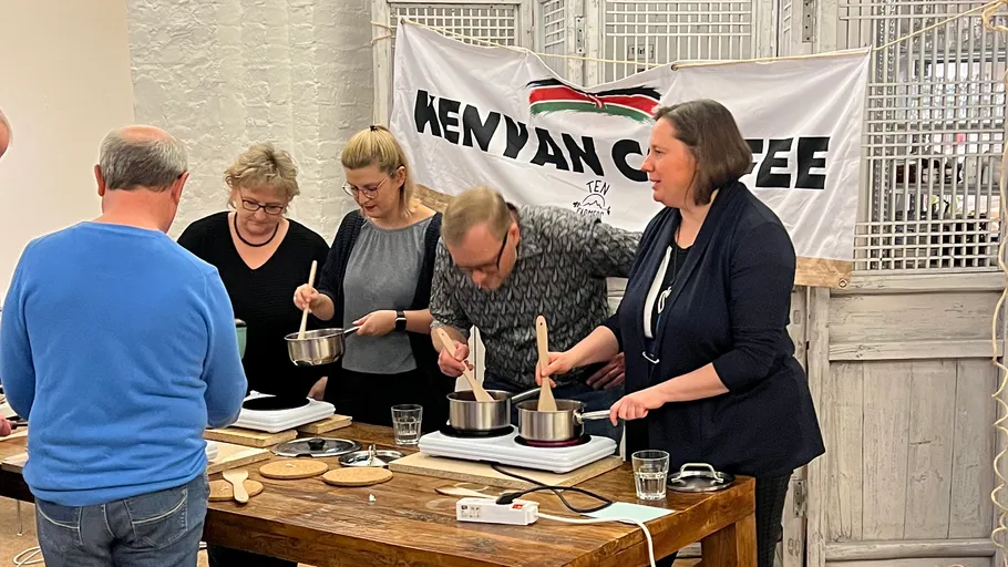 Group cooking with pots at table, Kenyan coffee banner.