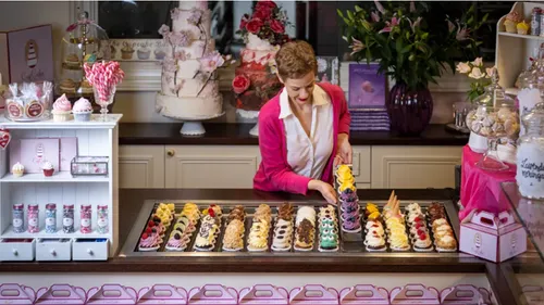Woman arranging colorful pastries in bakery.