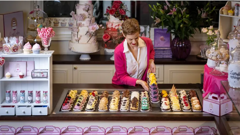 Woman arranging colorful pastries in bakery.