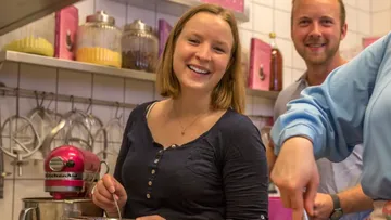 Menschen lächeln und kochen in einer Küche.