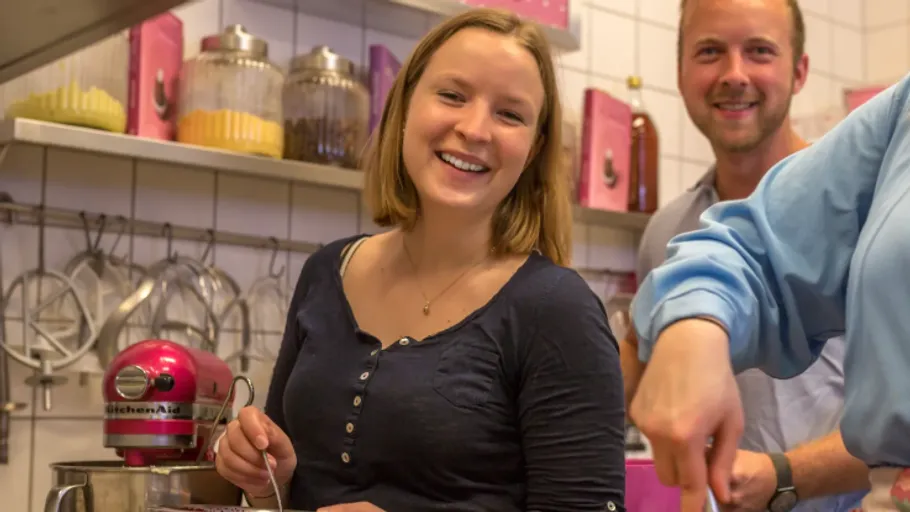 Menschen lächeln und kochen in einer Küche.