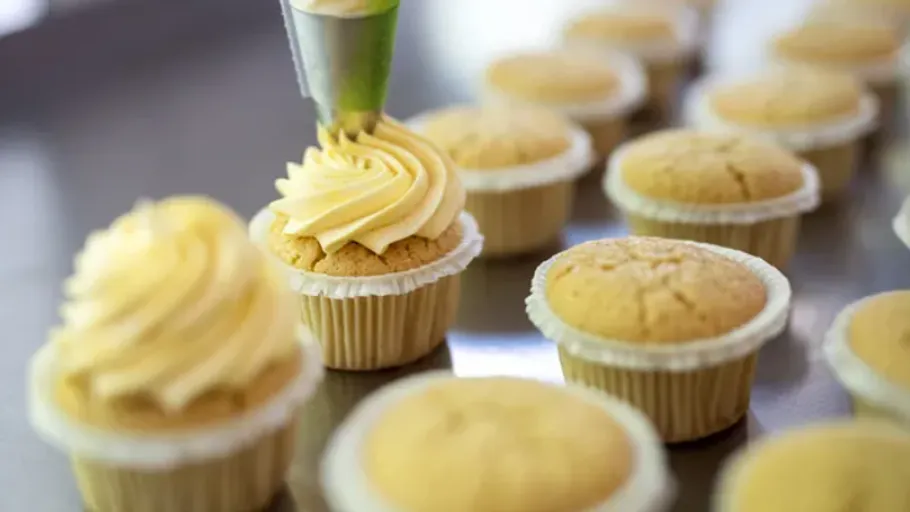 Cupcake being frosted in a bakery setting.