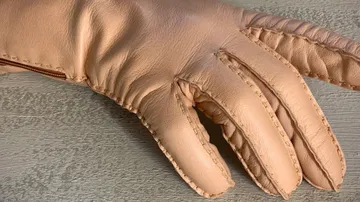 Beiger Lederhandschuh auf grauer Oberfläche.