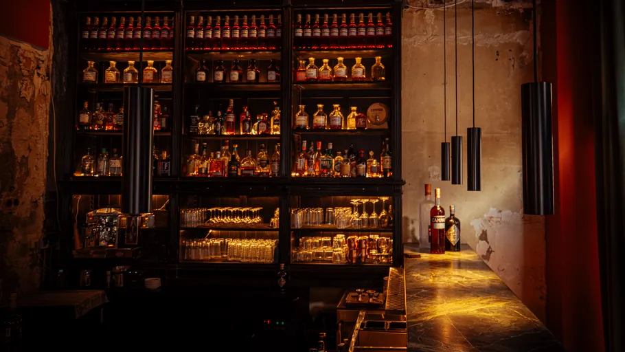 Dimly lit bar with bottles and glasses.