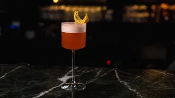 Cocktail mit Zitrusgarnitur auf dunkler Theke.