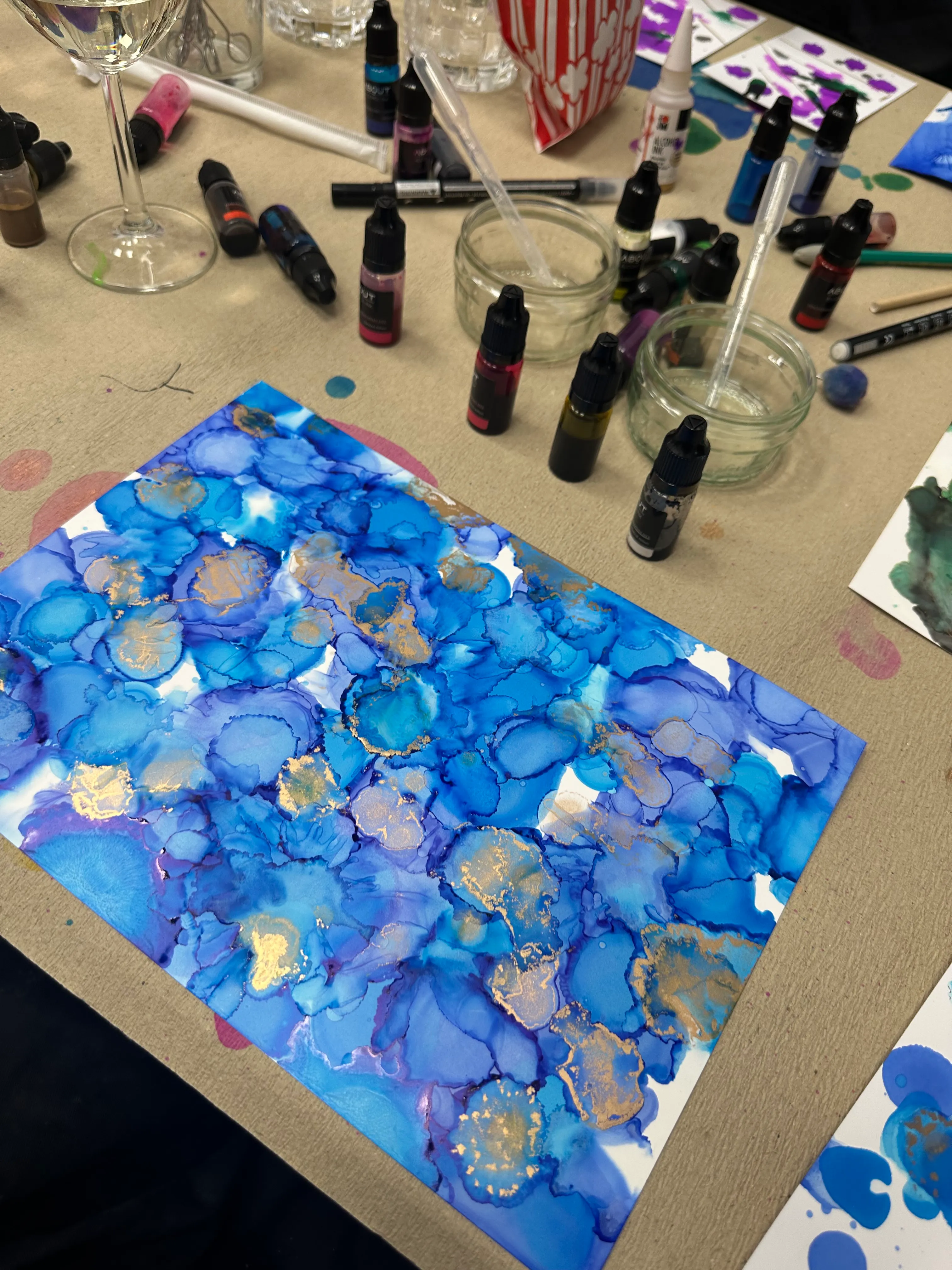 Blue ink art surrounded by art supplies.