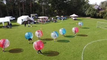 Menschen in Bubble-Bällen spielen Fußball auf Rasen.