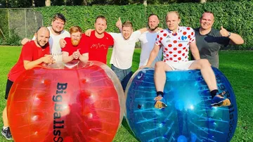 Men posing with inflatable balls on grass field.