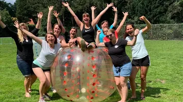 Group celebrating outdoors with bubble soccer ball.