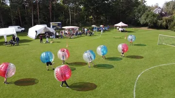 People playing bubble soccer on a field.