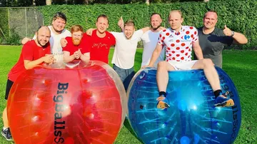 Group posing with two large inflatable balls outdoors.