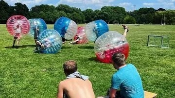 Menschen in Bubble-Anzügen auf einer Wiese spielen.