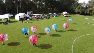 People playing bubble football on grass field.