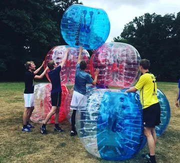 People stacking colorful inflatable balls outdoors.
