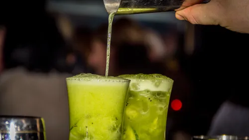 Grüne Cocktails werden in Gläser gegossen.