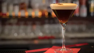 Espresso martini on bar counter with lights.