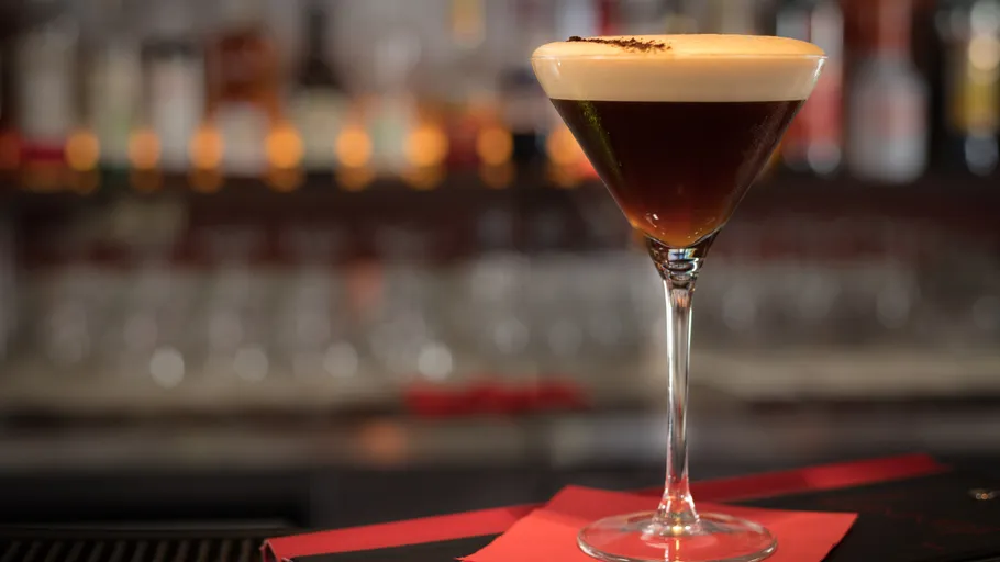 Espresso martini on bar counter with lights.