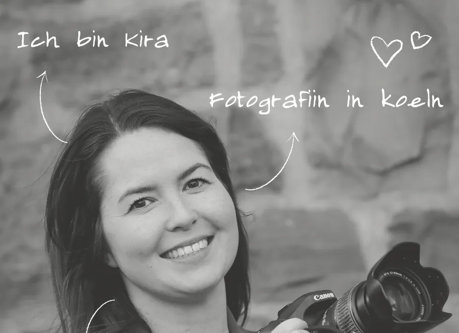Smiling woman holding camera, wall background.