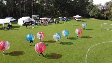 Menschen spielen Bubble-Fußball auf einem Feld.
