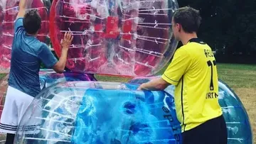 Men preparing for bubble soccer outdoors.