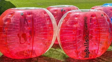 Red inflatable balls on grassy field.