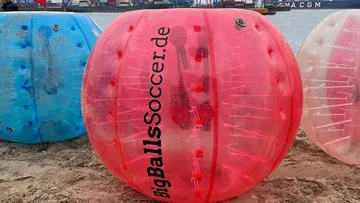 Giant inflatable balls on sandy beach.