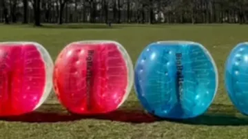 Vier aufblasbare Bälle auf einer Wiese.