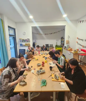 Group creating pottery around long table.