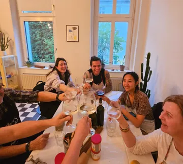 Gruppe stößt an einem Tisch in einem Raum an.