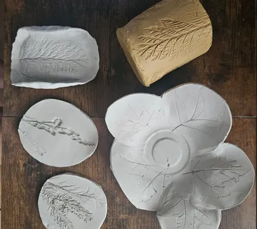 Clay pots with leaf imprints on wooden table.