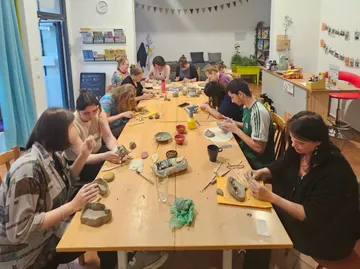 People crafting clay sculptures around table.
