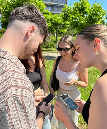 People using smartphones outdoors in a park.