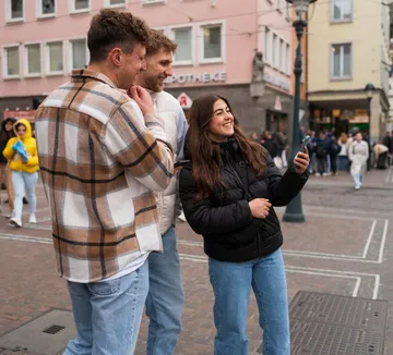 Drei Personen machen Selfie in urbaner Straße.