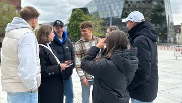 Gruppe von Menschen spricht auf Stadtplatz.
