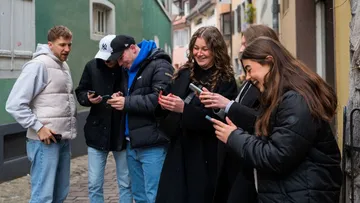 Gruppe von Personen schaut auf Handys in Straße.