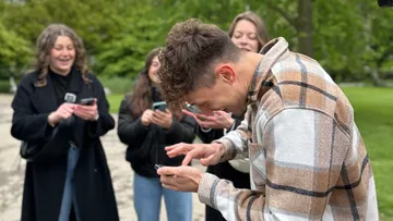 People laughing and using phones in a park.