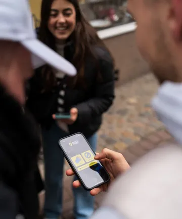 Person nutzt Smartphone auf Kopfsteinpflaster.