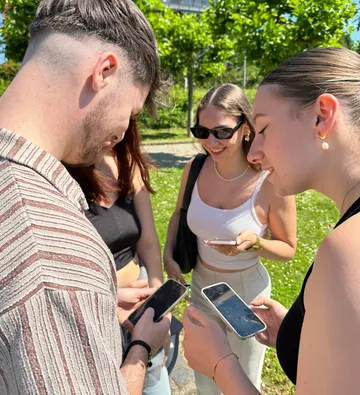 Group using smartphones outside on a sunny day.