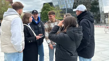 Gruppe von Personen steht draußen und spricht.