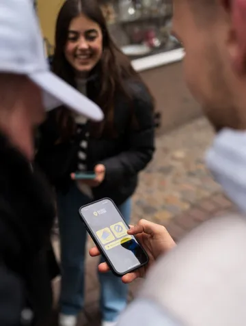 Person using phone app, others smiling nearby.