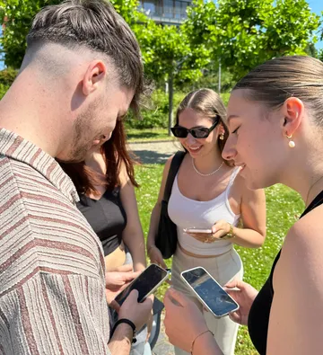 Group of friends looking at phones outside.