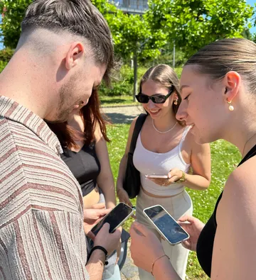 Group of friends looking at smartphones outside.