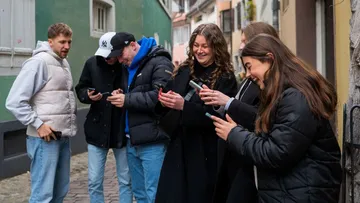 Group of people using smartphones on a street.