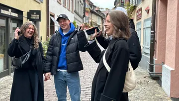 Group of people laughing with phones in street.