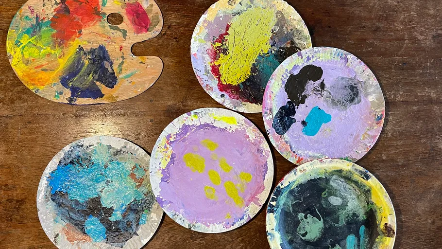 Paint palettes with mixed colors on table.