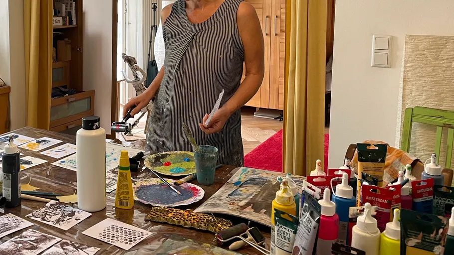 Woman painting in art studio with supplies.