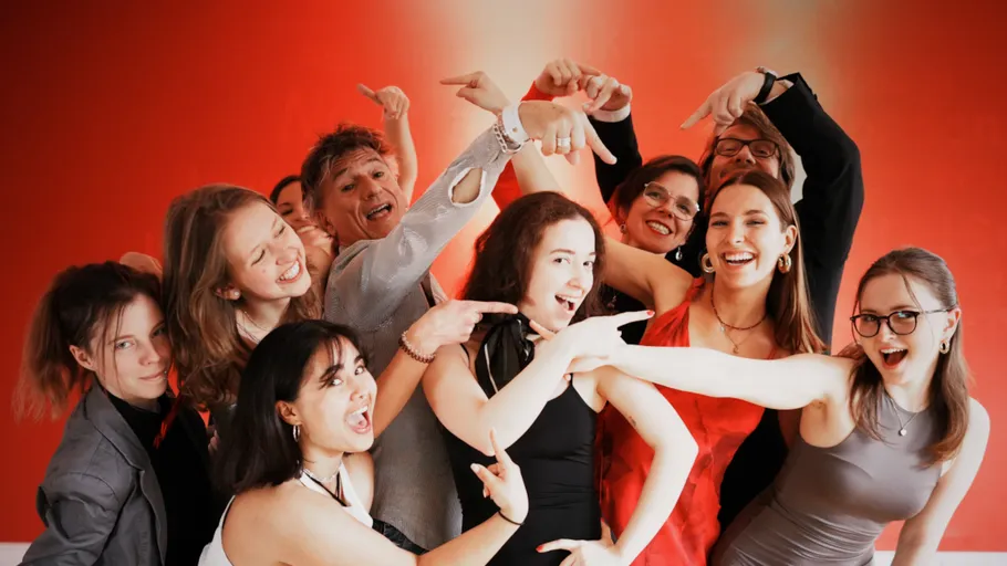 Gruppe von Menschen lächelt, zeigt im roten Raum.