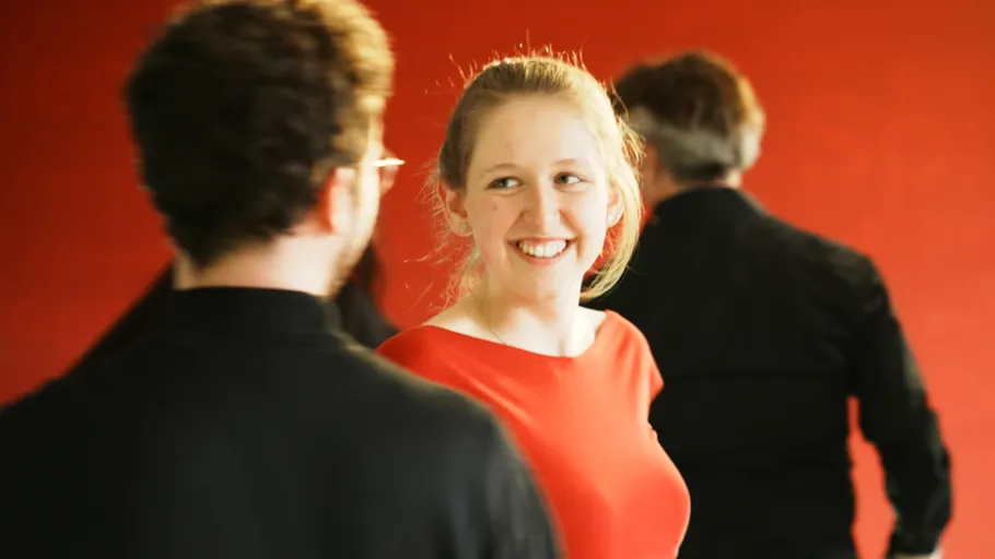 Smiling woman in red dress with people.
